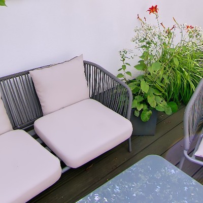 Outdoor lounge sofa and flowering planters on the roof terrace