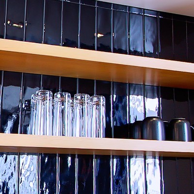 Glassware and crockery on the kitchen's black-tiled open shelving